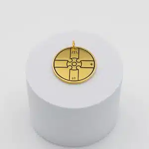 Médaillon Keargwen doré posé sur un socle blanc, motif géométrique gravé