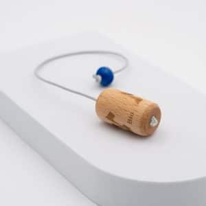 Pendule biologique bT sur un présentoir blanc, cylindre de hêtre gravé et perle bleue